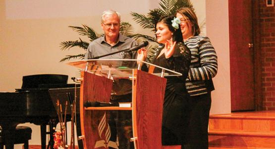 Michelle “Shelby” Muyango (center), joined by Pastor John Kent and Karen Schneider, shares her testimony. Michelle “Shelby” Muyango (center), joined by Pastor John Kent and Karen Schneider, shares her testimony.
