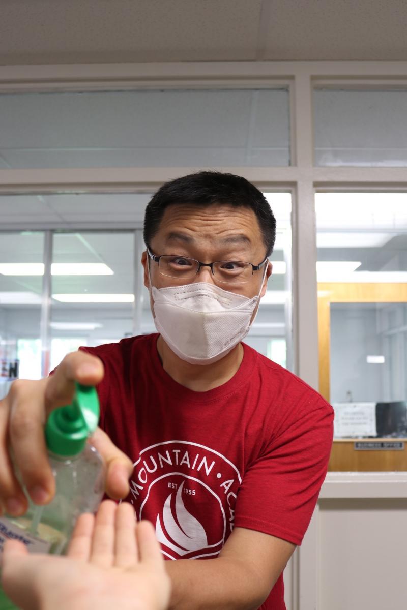 Blue Mountain Academy Chaplain SangHae Kim offers hand sanitizer to a student