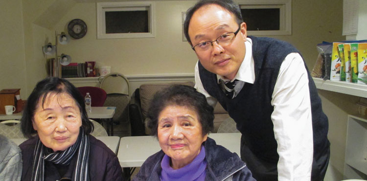 Seungho Park, pastor of Allegheny East Conference’s Delaware Korean church in Newark, assists Susie Ra and Myungja Kim during a computer class held at the church’s community center. 